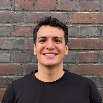 Leo, founder of Power Up, smiling in front of a brick wall